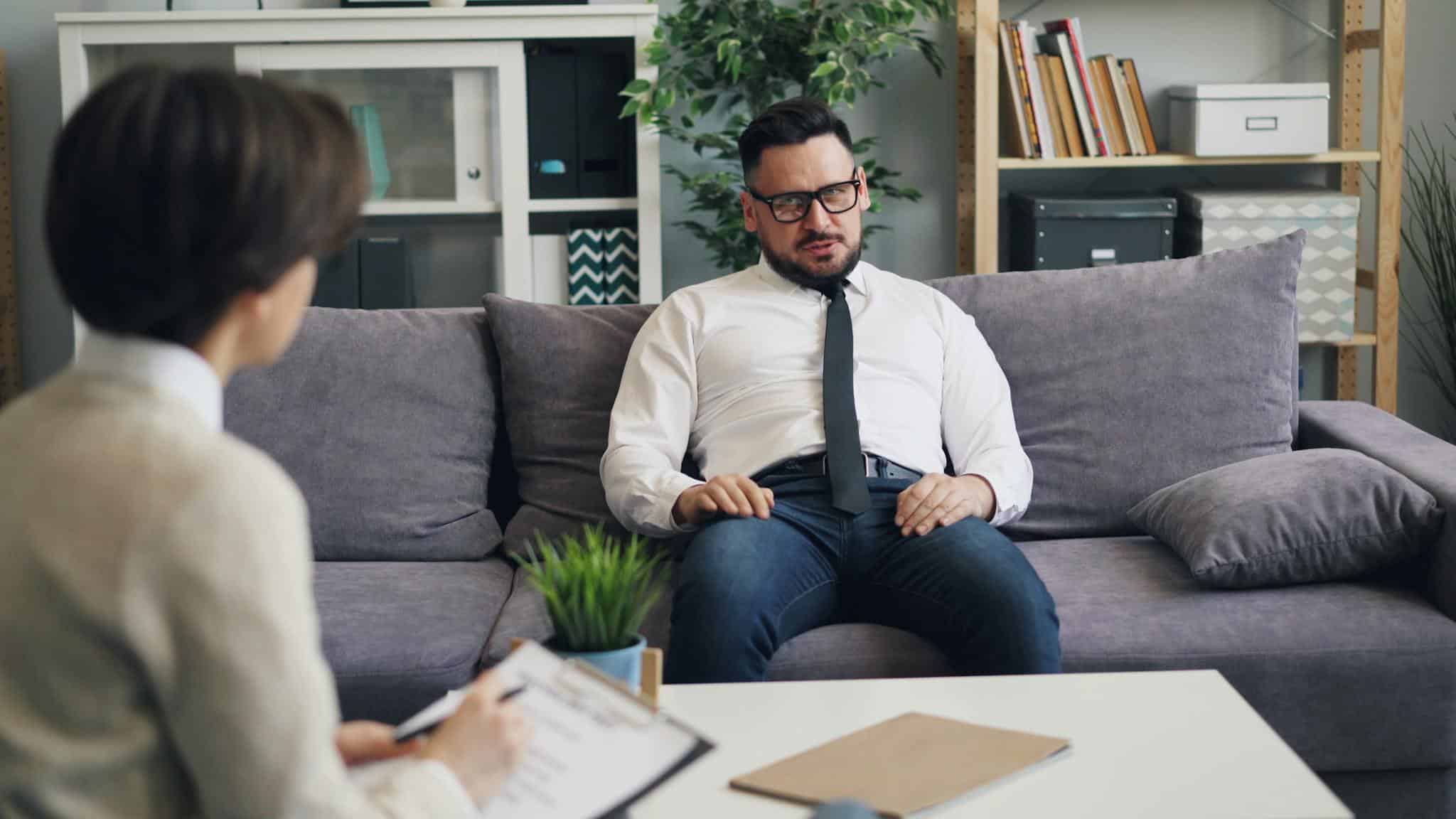 Man having a therapy session with a psychologist in a cozy office environment.